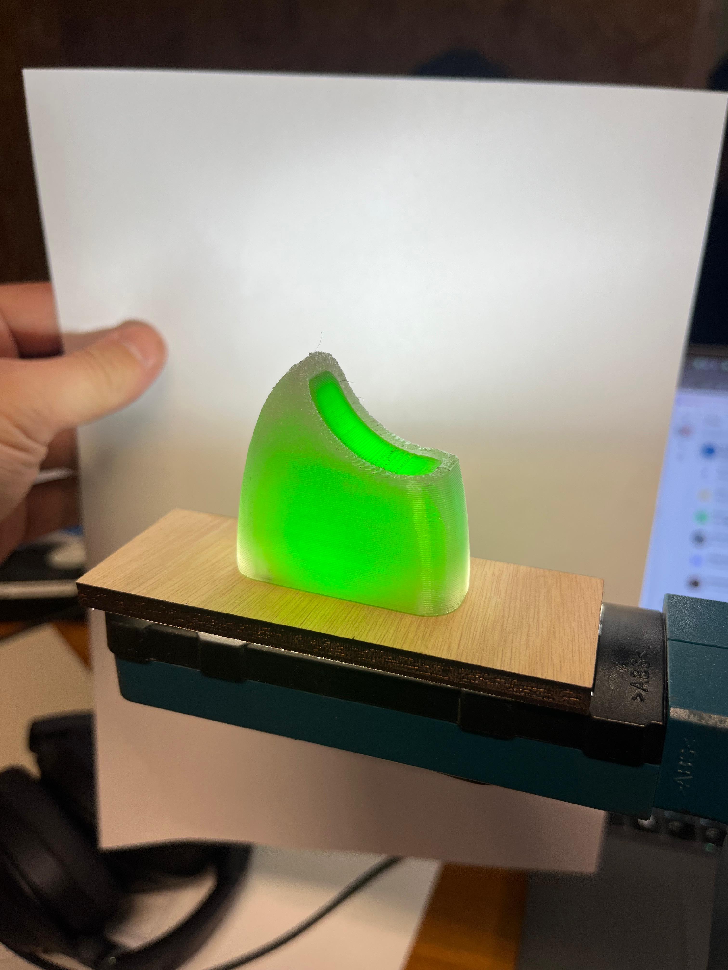 A 3D printed popsicle tip lit from below by a work light to test light emission